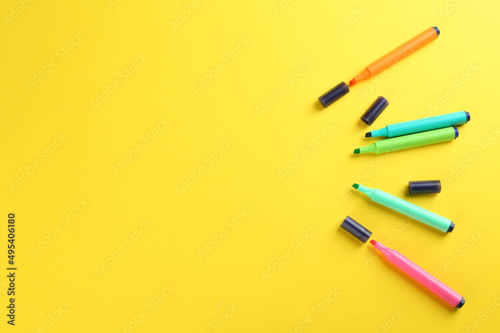 Many colorful markers on yellow background, flat lay. Space for text