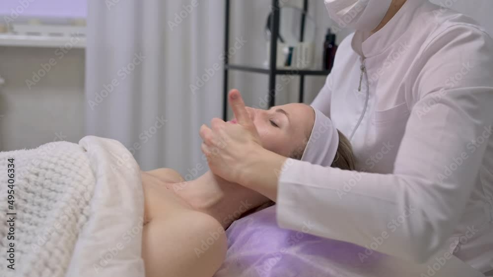 Young beautiful woman is massaged face in spa salon. Face massage essential oil for skincare Young beautiful woman is massaged face in spa salon. Face massage essential oil for skincare
