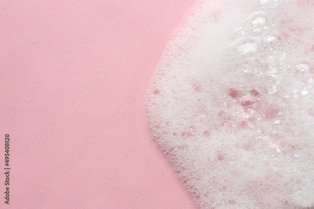 Fototapeta premium Fluffy bath foam on pink background, top view. Space for text