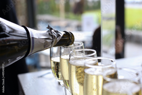 Pouring champagne from bottle into many glasses to celebrate the holiday after the wedding ceremony closeup