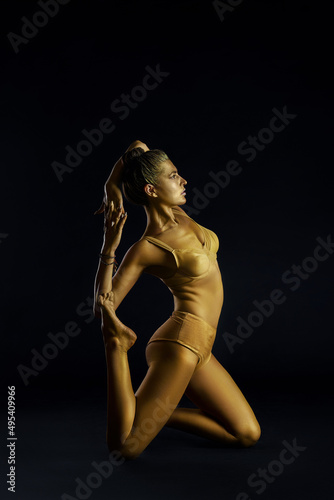 Yoga woman gold body, spiritual and physical practices. Judaism exercises body and soul.  Fitness woman yoga. Healthy life and natural balance between body and mental development. Black background © angel_nt