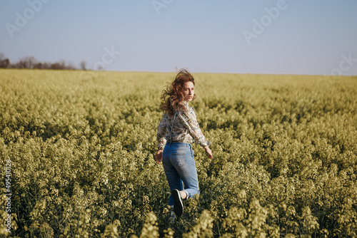 Woman run away through the flowering field and looking back photo