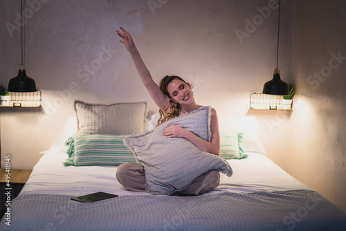 Chica joven sonriendo feliz sobre la cama de un hotel mientras viaja photo