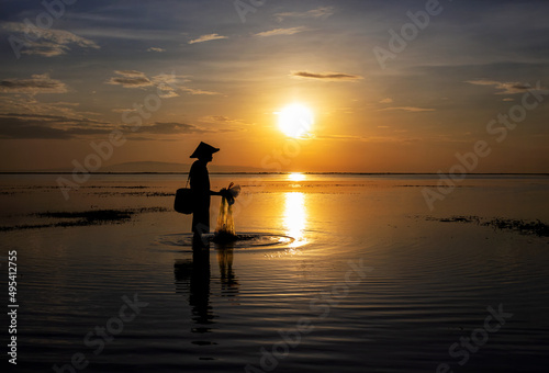 Silhouette Balinese male fishing Indonesian coastline at sunrise