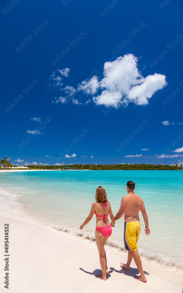 Carefree Caucasian couple barefoot on luxury beach together