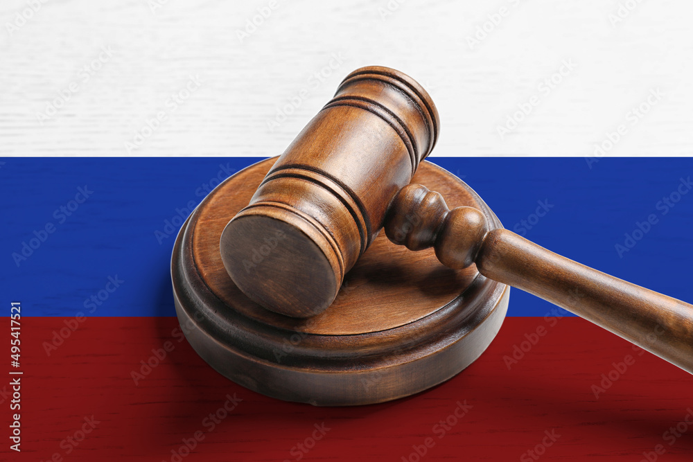 Judge's gavel on wooden background in color of Russian flag. Concept of sanctions against Russia
