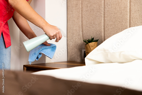 Maid cleans the hotel room with disinfectant and a cloth.