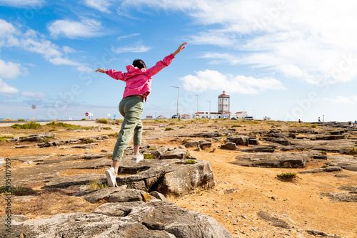 Girl jumping on rocks with arms outstretched in Carvoeiro cape