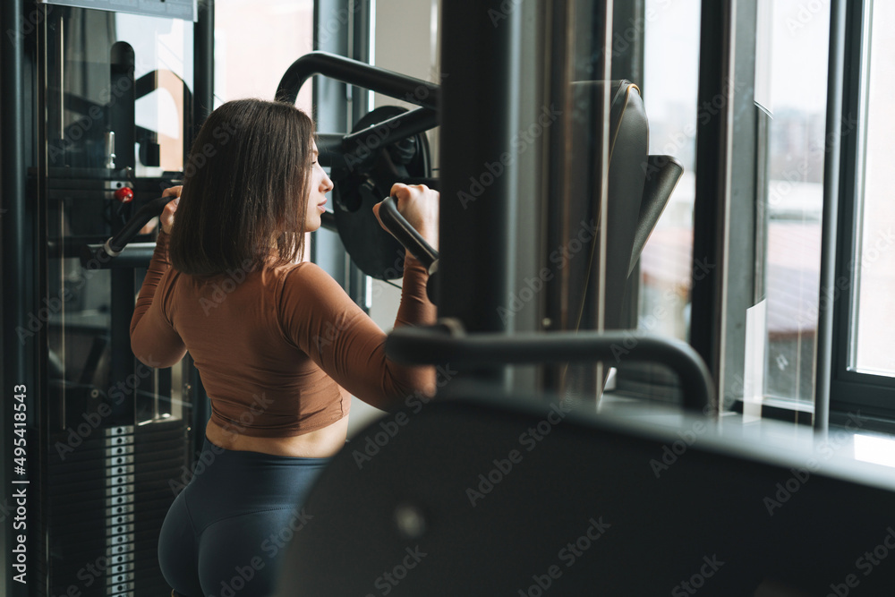 Young fitness brunette woman training for back muscles equipment at the gym Young fitness brunette woman training for back muscles equipment at the gym