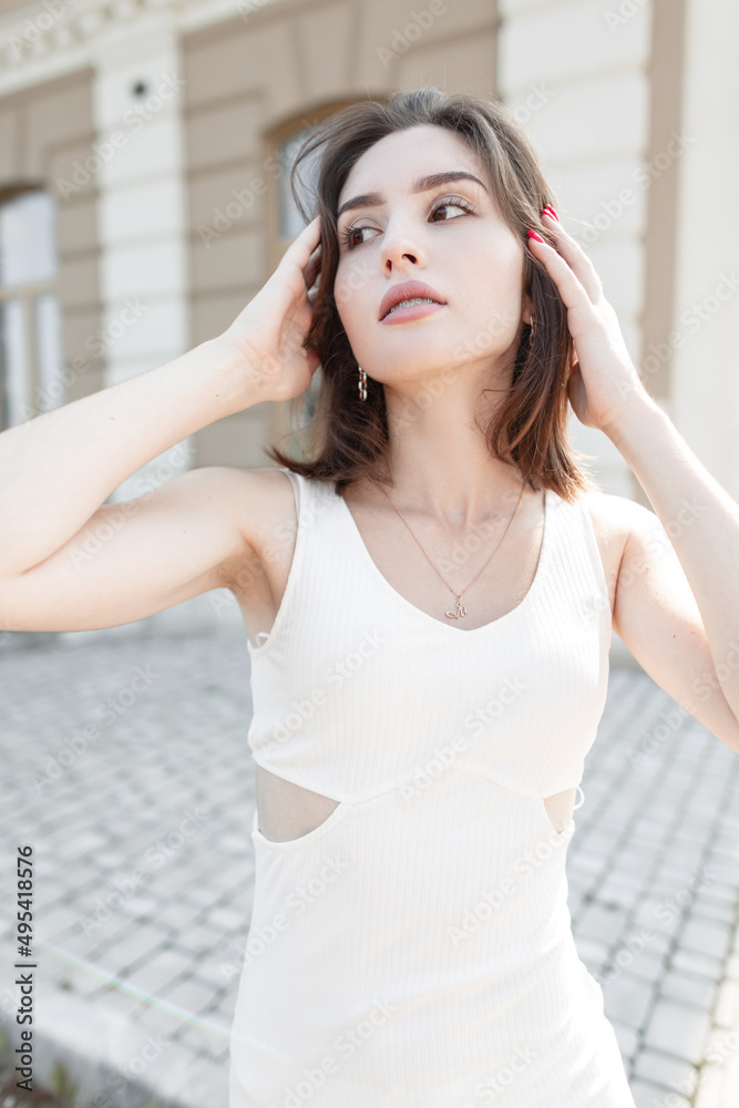 Fashionable beautiful stylish model girl with a short haircut in a fashion white dress walking and posing in the city Fashionable beautiful stylish model girl with a short haircut in a fashion white dress walking and posing in the city