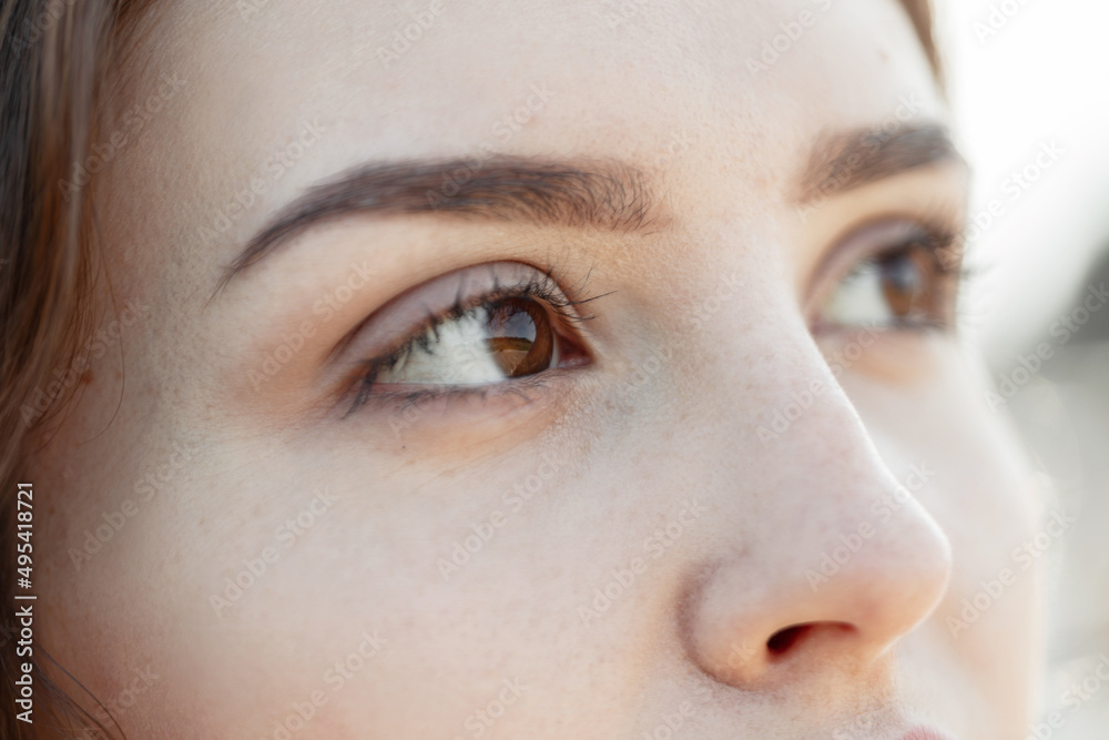 Fototapeta premium Beautiful woman with clear skin and brown eyes on a warm summer day. A woman's brown eyes