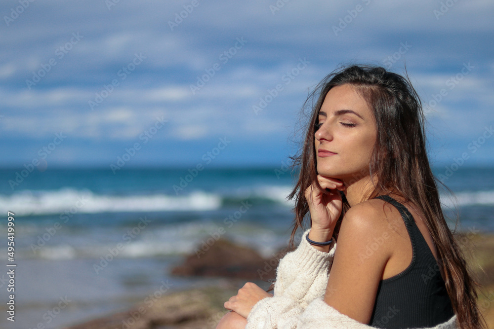 Young and brunette woman sunbathing relaxed with her eyes closed at the beach