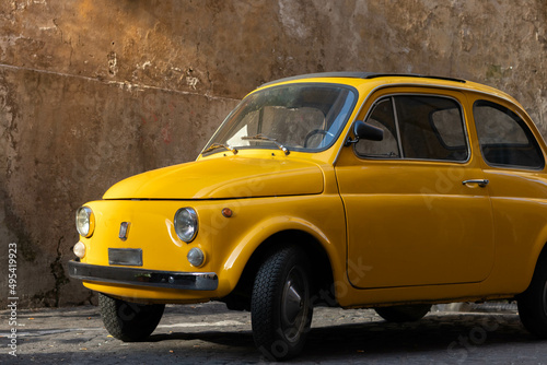 Photography Antique vintage yellow 500 car in the streets of Trastevere in Rome, Italy