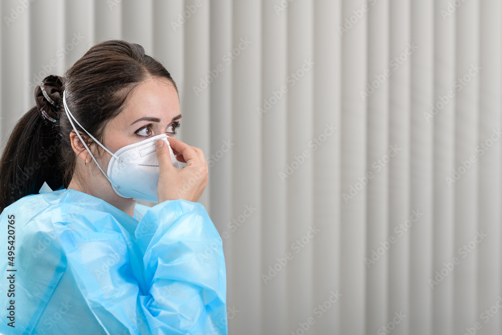 Female doctor adjusting Covid-19 N95 mask in admissions office before patient visits