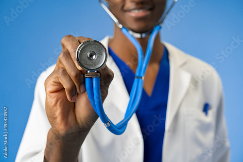Cropped photo of black medical doctor with stethoscope on blue