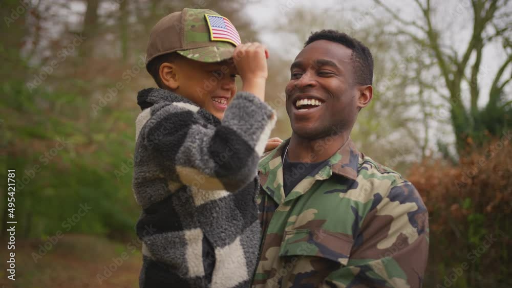 American soldier coming home on leave with son trying on his army uniform cap outdoors - shot in slow motion