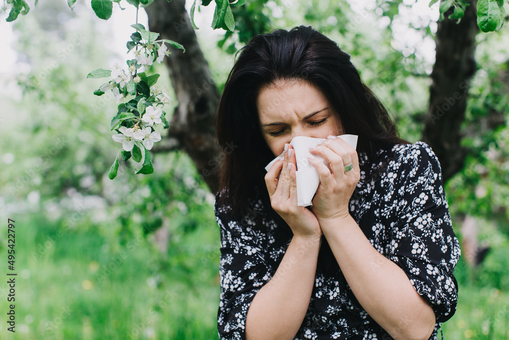 A young woman with an allergy sneezing into handkerchief. Concept: Allergy season A young woman with an allergy sneezing into handkerchief. Concept: Allergy season