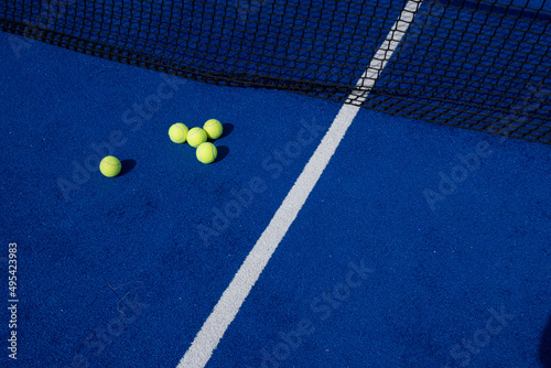 Canvas Print five paddle tennis balls and the net of a blue paddle tennis court, selective fo