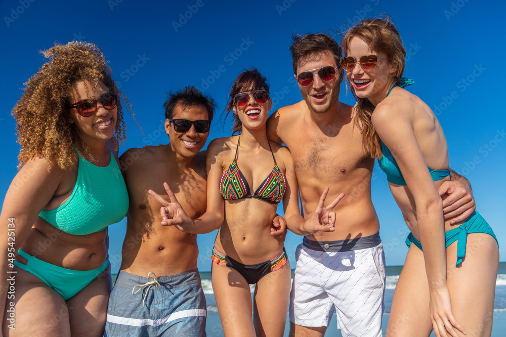 Fun loving friends group on beach in swimwear