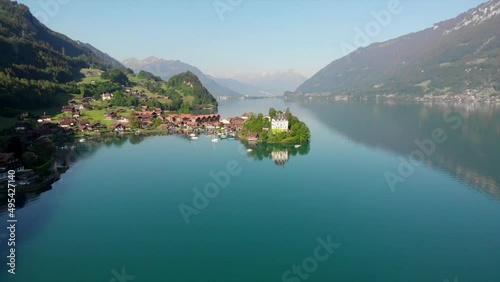 Droneview to famous village Iseltwald, Switzerland with the castle Seeburg. Early morning light with the buildings reflecting in the water. photo