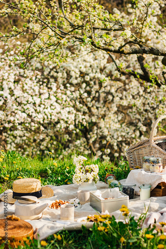 Breakfast picnic with waffles and tea in spring blossom garden on a white tablecloth on a sunny day, cherry blossoms. Outdoor, picnic, brunch, spring mood