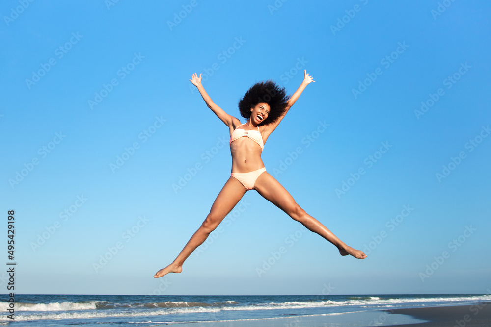 Young Afro American woman jumping high on beach