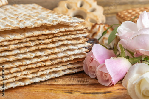Pink roses on the background of traditional food for Jewish holiday Pesach matzah.