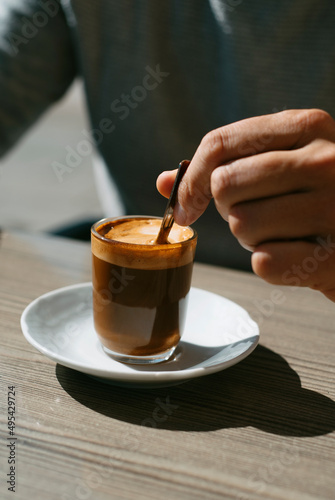 man stirring his machiatto with a coffee spoon