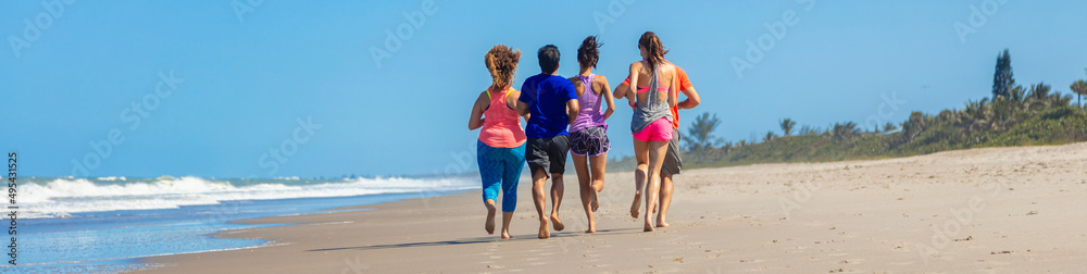 Panoramic view of friends jogging together on beach