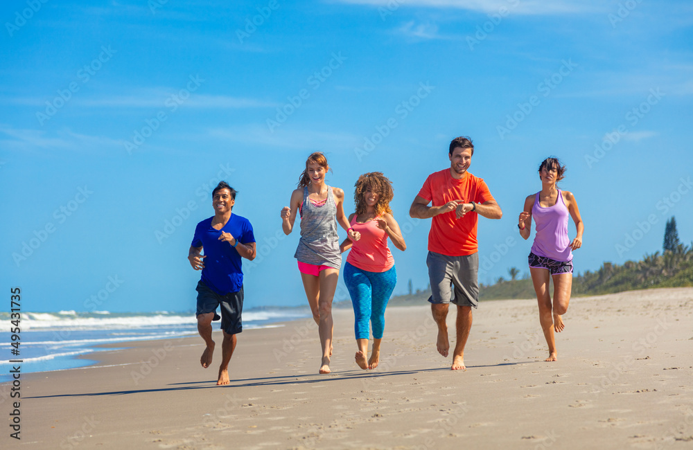 Friends with healthy lifestyles jogging barefoot over sand Friends with healthy lifestyles jogging barefoot over sand