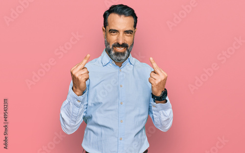 Middle aged man with beard wearing business shirt showing middle finger doing fuck you bad expression, provocation and rude attitude. screaming excited