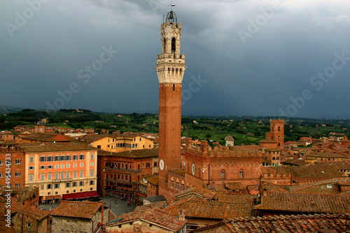 Tower of Mangia on Piazza del Campo against the backdrop of a stormy sky in the medieval city of Siena, Tuscany, Italy