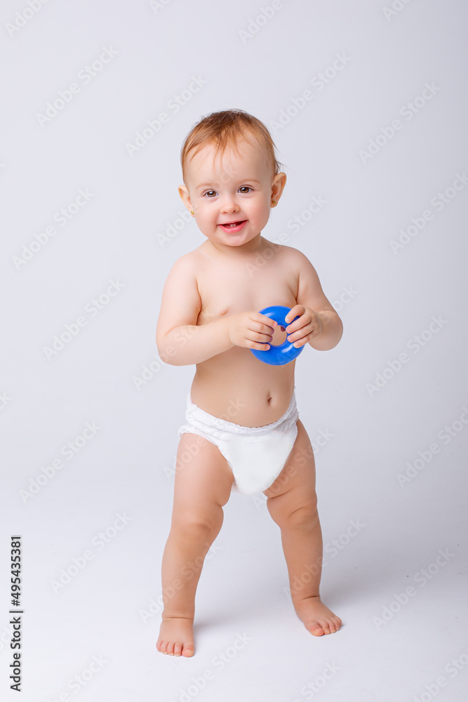 cute baby girl in a diaper stands in full height isolated on a white background