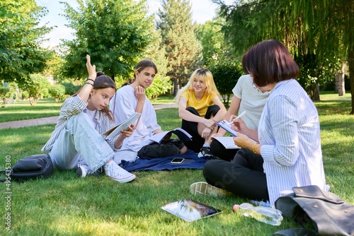 Outdoor, group of students with female teacher sitting on grass