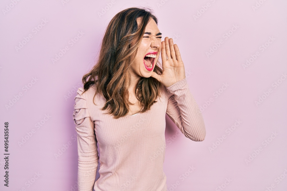 Young hispanic girl wearing casual clothes shouting and screaming loud to side with hand on mouth. communication concept. Young hispanic girl wearing casual clothes shouting and screaming loud to side with hand on mouth. communication concept.