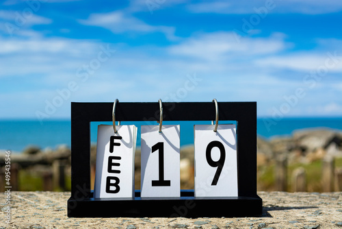 Feb 19 calendar date text on wooden frame with blurred background of ocean