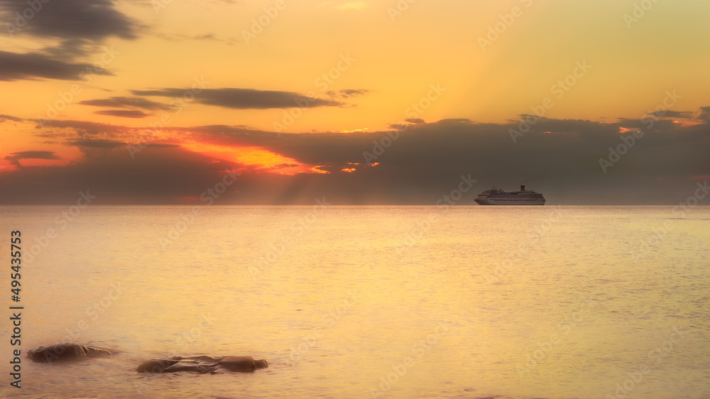 sea at sunset with far away cruise ship