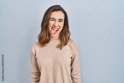 Young woman standing over isolated background sticking tongue out happy with funny expression. emotion concept.