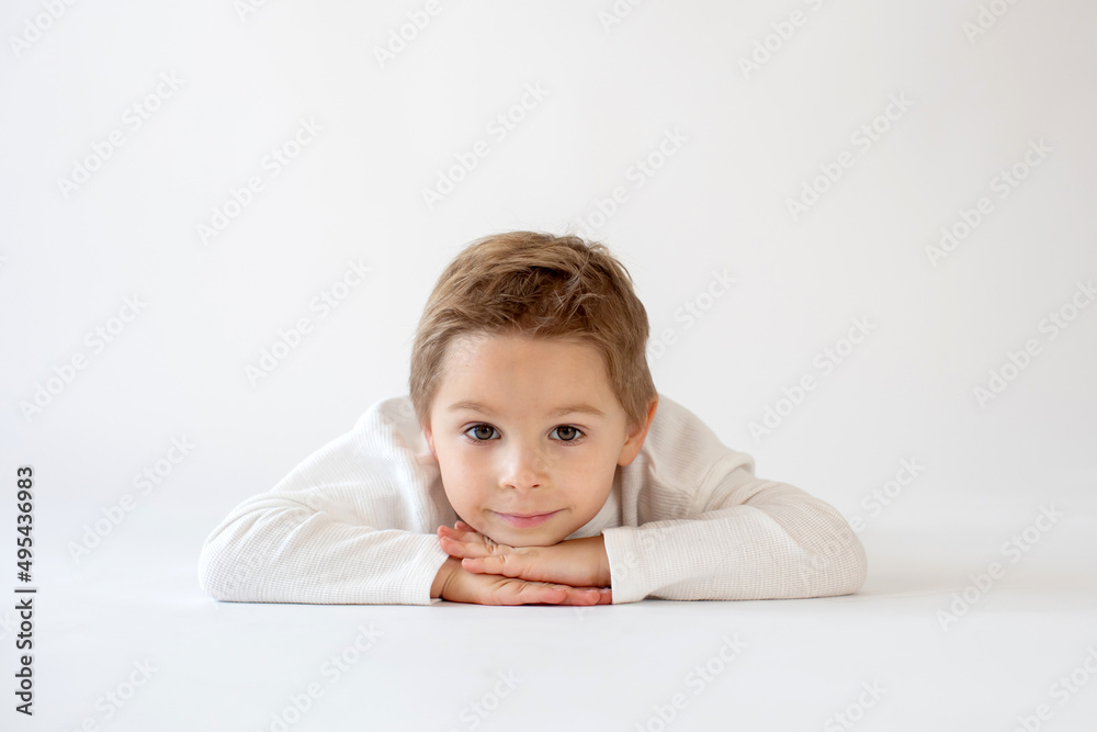 Cute stylish toddler child and older brothers, boys with white shirts on white background, family kids portrait Cute stylish toddler child and older brothers, boys with white shirts on white background, family kids portrait