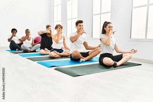 Group of young people smiling happy training yoga nadi shodhana breath at sport center.