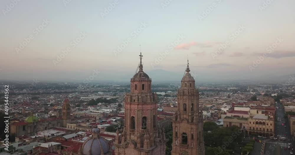 Drone flies over Morelia, Michoacan, Mexico at sunrise. Drone panning left as birds fly around the cathedral spires with the city in the background. Drone flies over Morelia, Michoacan, Mexico at sunrise. Drone panning left as birds fly around the cathedral spires with the city in the background.