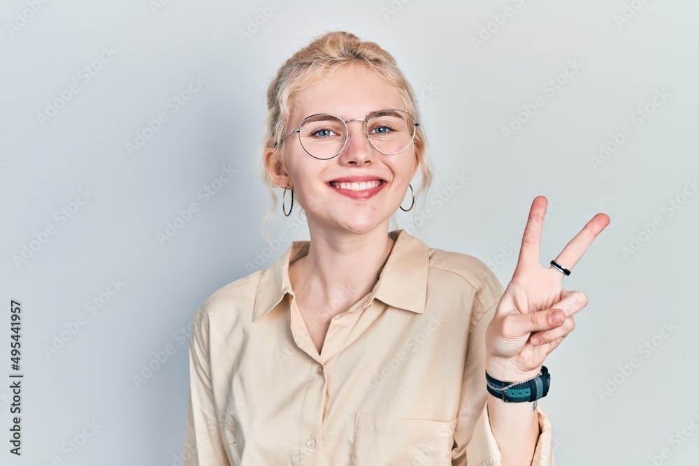 Beautiful caucasian woman with blond hair wearing casual look and glasses showing and pointing up with fingers number two while smiling confident and happy. Beautiful caucasian woman with blond hair wearing casual look and glasses showing and pointing up with fingers number two while smiling confident and happy.