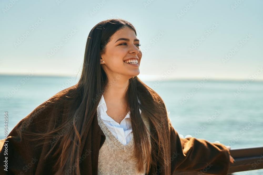 Young hispanic woman smiling happy leaning on the balustrade at the beach. Young hispanic woman smiling happy leaning on the balustrade at the beach.