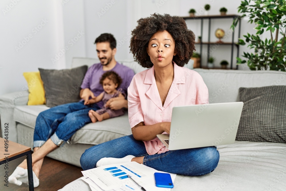 Mother of interracial family working using computer laptop at home making fish face with lips, crazy and comical gesture. funny expression. Mother of interracial family working using computer laptop at home making fish face with lips, crazy and comical gesture. funny expression.
