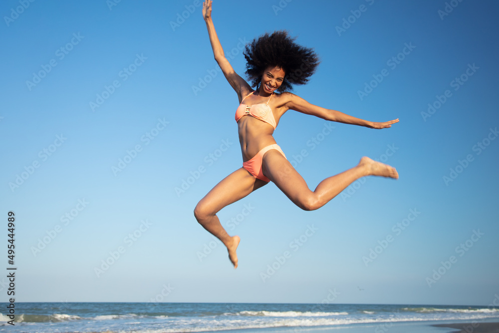 Fun loving Afro female jumping by the ocean Fun loving Afro female jumping by the ocean