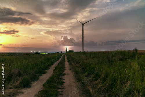 Photograph of large wind turbines in a row in the meadow during a lightning storm