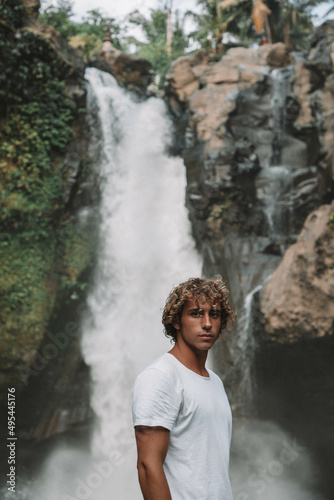 Portrait of young man standing in front of waterfall photo
