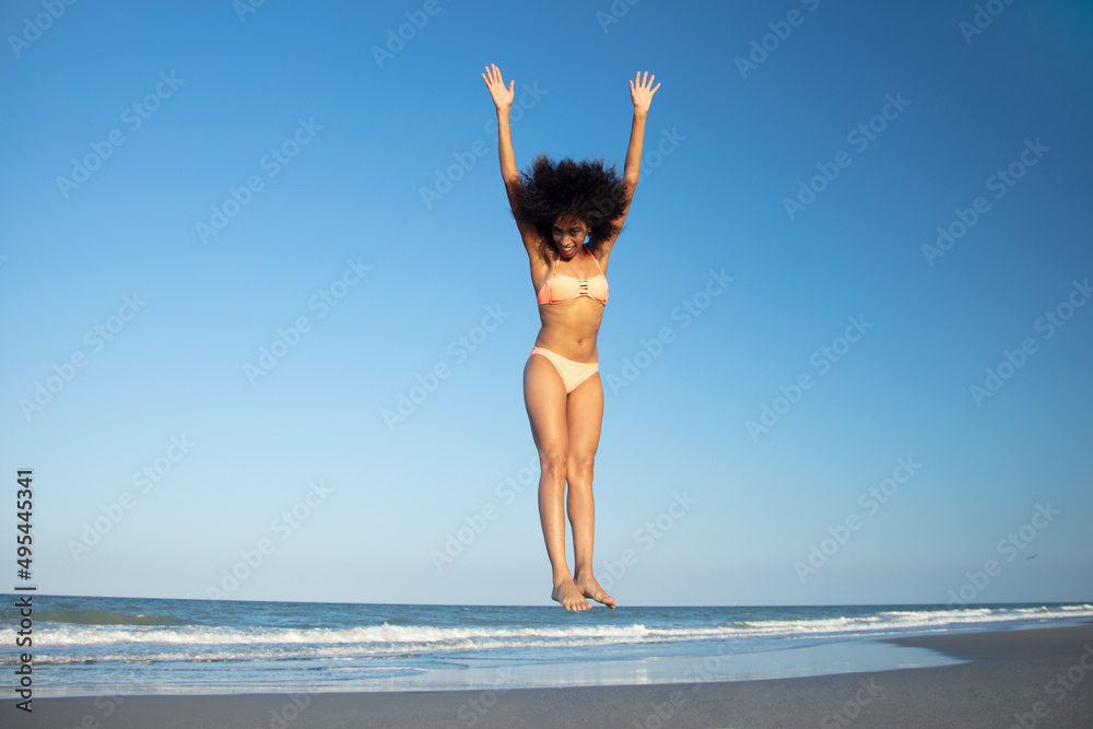 Afro American woman in swimwear jumping for joy Afro American woman in swimwear jumping for joy
