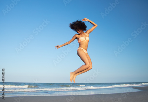 Afro American woman jumping for joy on beach