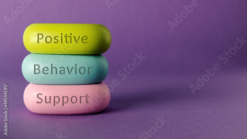 Positive behavior support words written on colorful wooden blocks. Purple background with copy space.